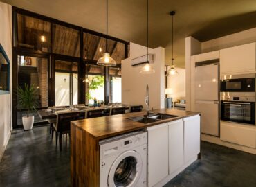 A well equipped and a modern kitchen with an oven standing cleaning area with a washing machine and a table.